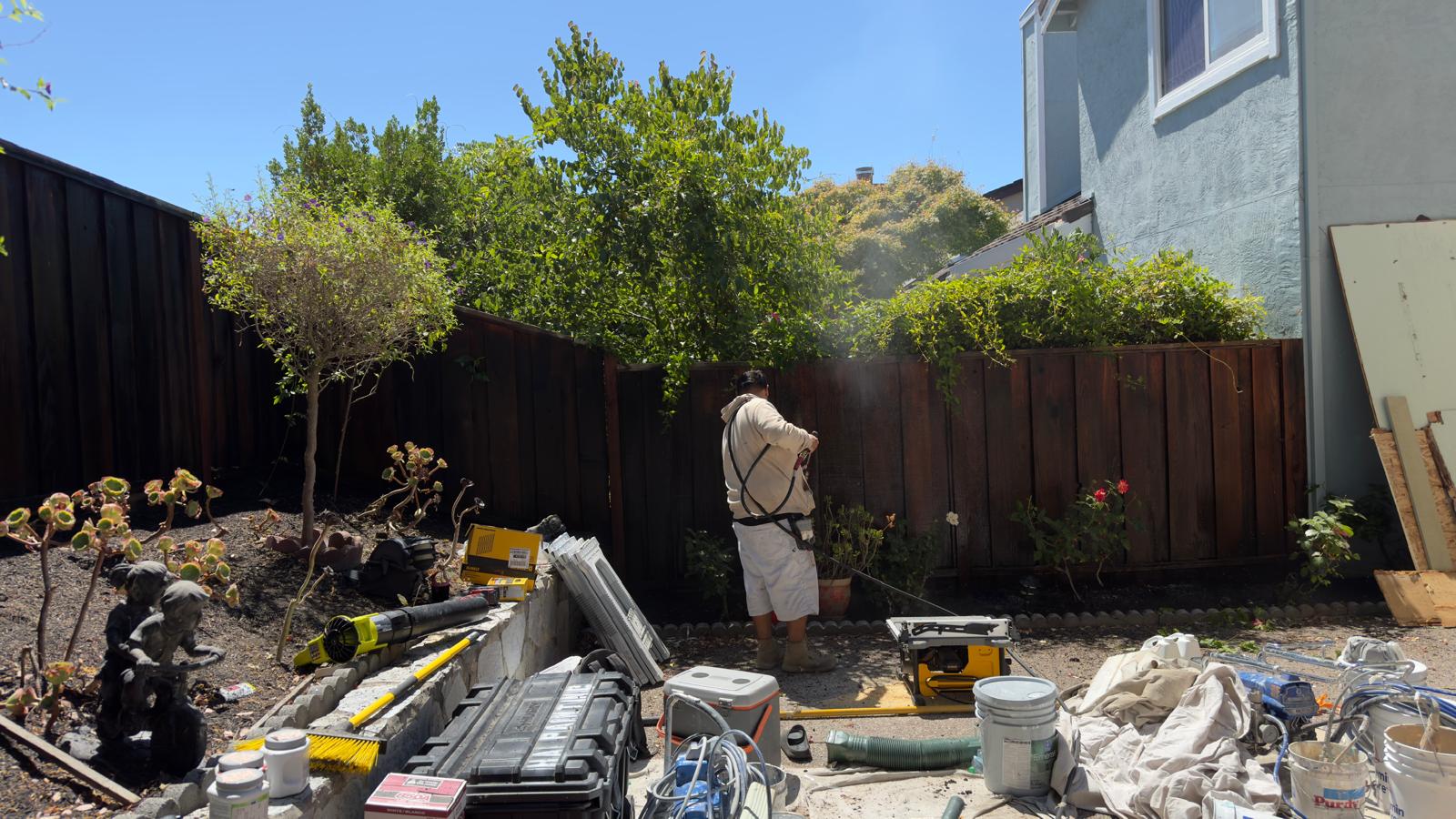 A H.A. painter power washing a fence in a Bay Area residential area