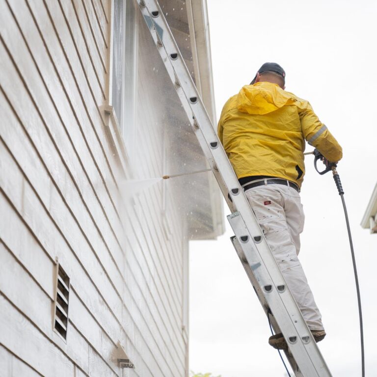H.A. Painting crew member power washing the exterior of a house before applying a fresh coat of paint