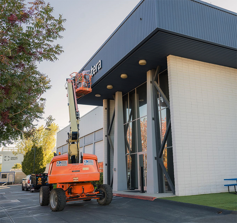 A painter near the Bay Area using a lift to repaint the signage on a commercial exterior